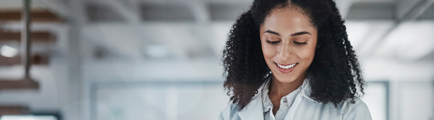 Woman with curls in a white coat looks at tablet